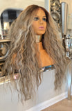 Mannequin head with long, wavy gray wig in a decorative setting.